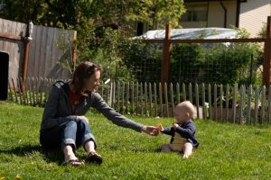 Kristin Page and her baby Fern play in their backyard that is filled with herbs, chickens, and vegetables. Photo by Emily Porter