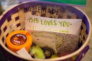 A basket with notes and gifts sits on a table, a note reads "1515 Loves You"